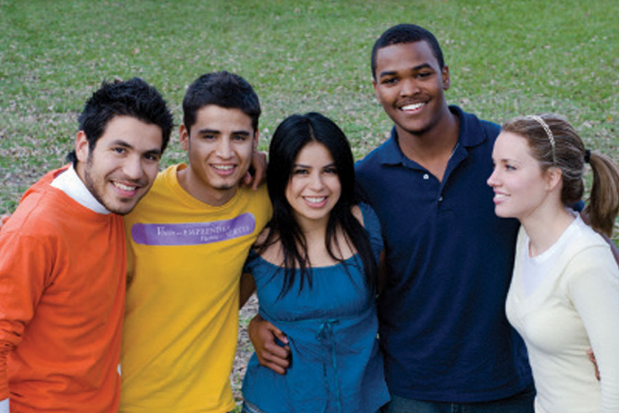 Diverse group of 5 teeanergs with their arms around each othee