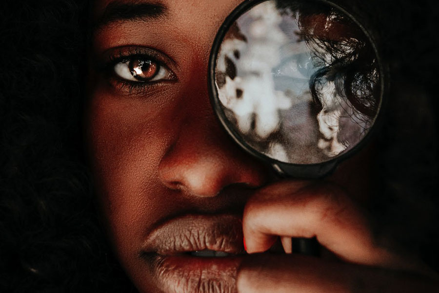 Black teen looking through magnifying glass